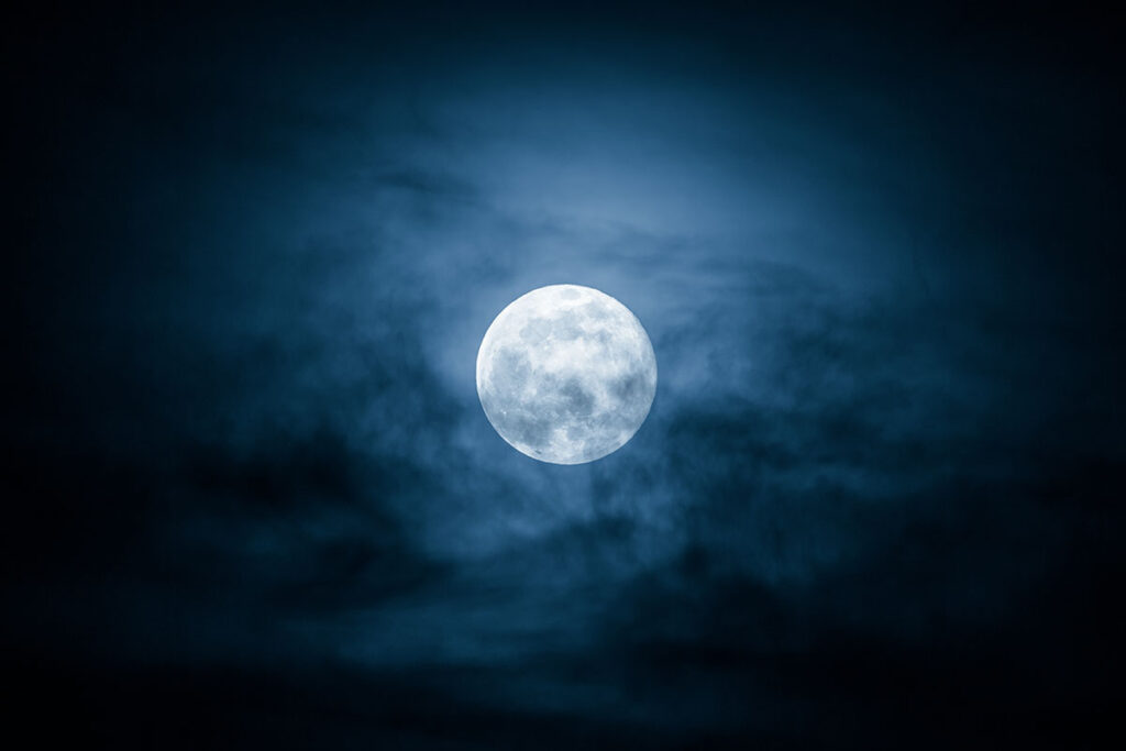 Moon hiding behind clouds at night.