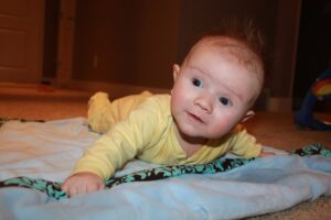Young baby on tummy on blanket crawling on floor